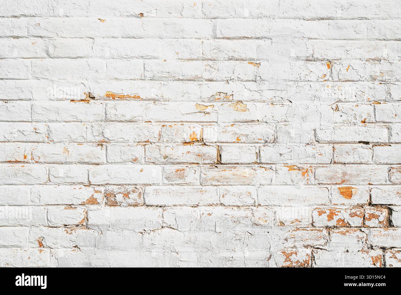 Aged whitewashed brick wall texture with flaking paint and exposed yellow surface underneath. Stock Photo