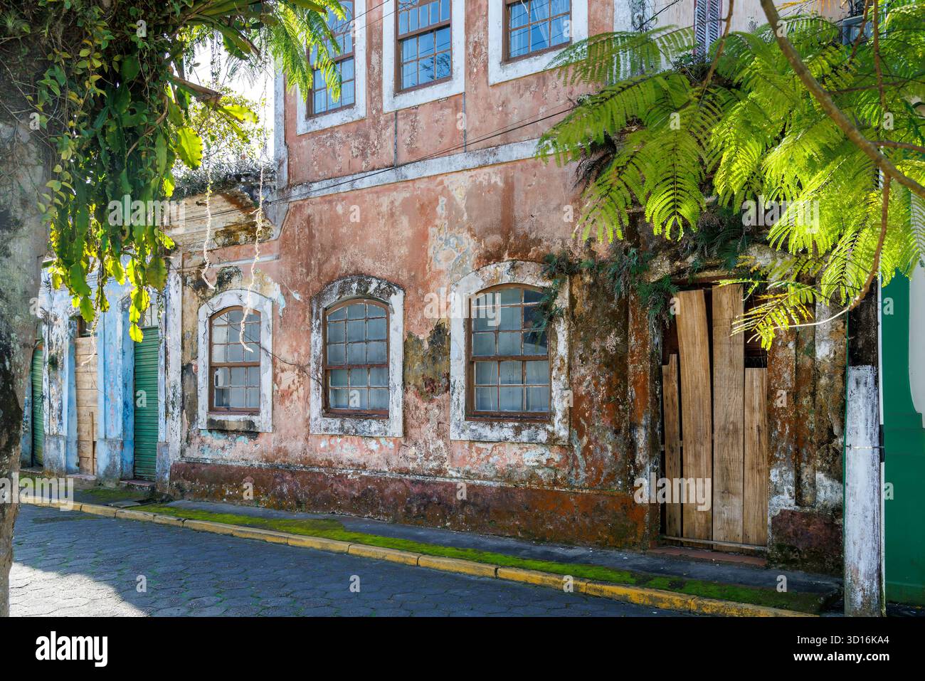 House with shuttered windows and fading paintwork, Cananeia, Brazil Stock Photo