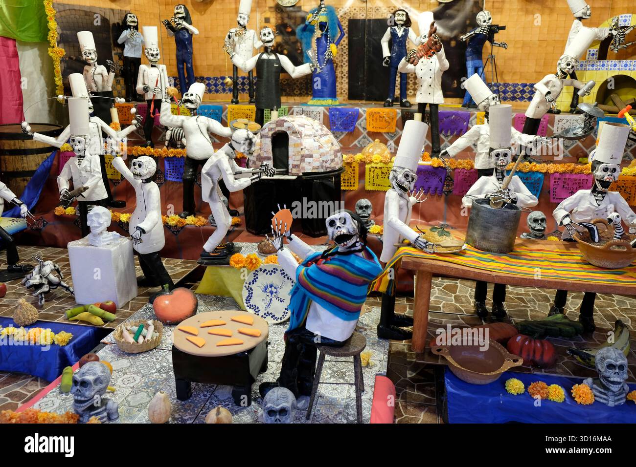 Colorful Day of the Dead display with skeleton figurines dressed as chefs and musicians surrounded by marigolds and traditional decorations Stock Photo