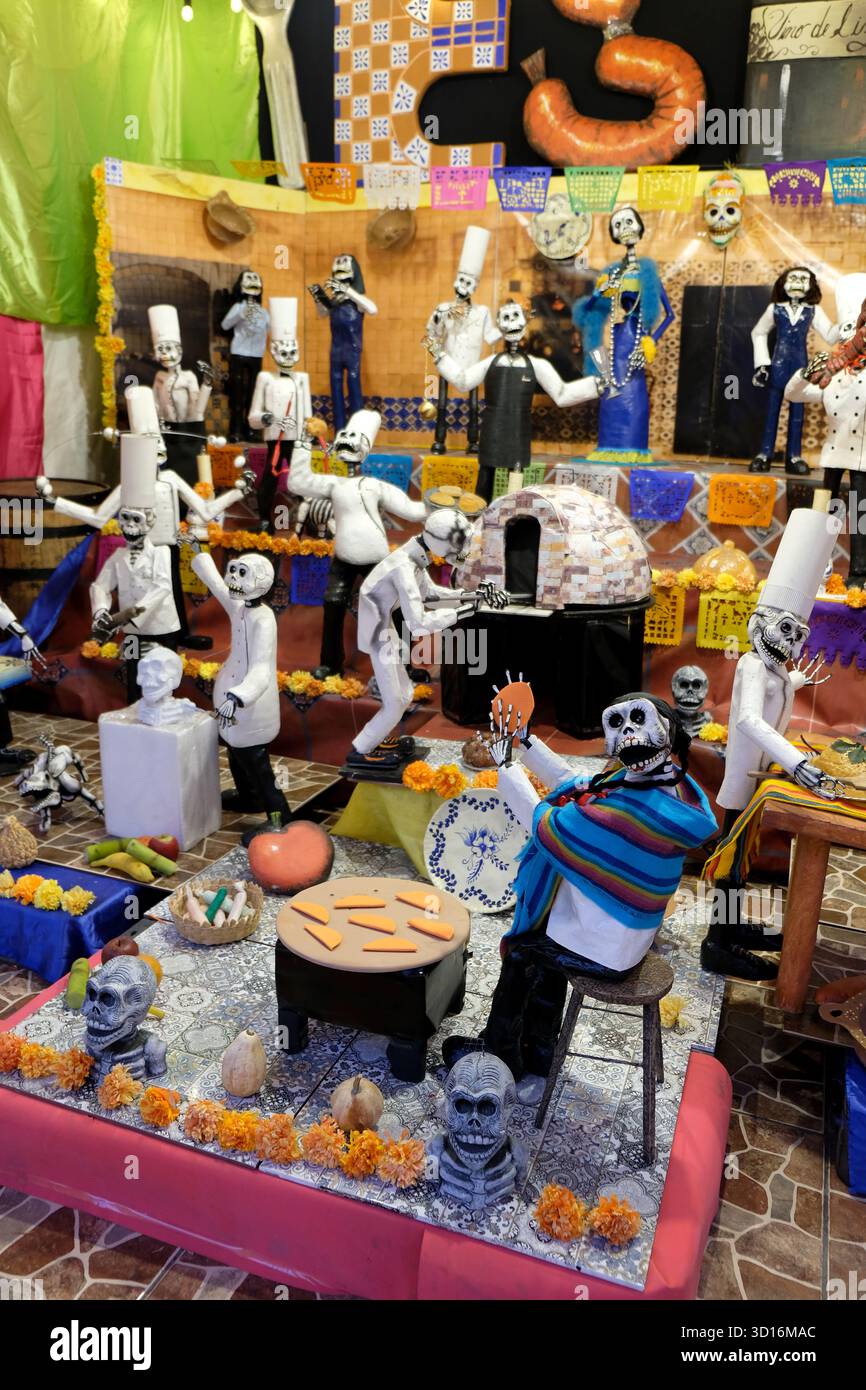 Colorful Day of the Dead display with skeleton figurines dressed as chefs and musicians surrounded by marigolds and traditional decorations Stock Photo