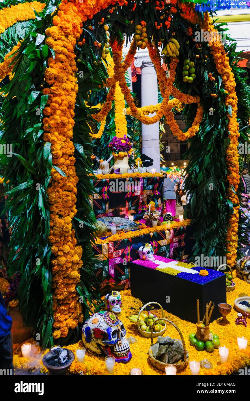Colorful Day of the Dead altar decorated with marigolds, sugar skulls, food offerings and candles during a cultural celebration Stock Photo