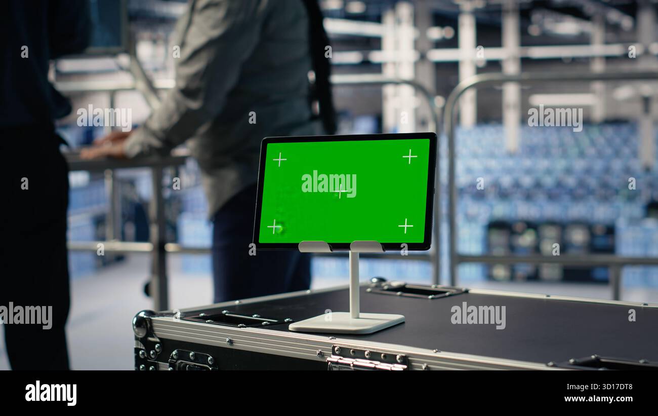 Data center IT professionals check AI dashboard using isolated screen tablet. Server room developers test artificial intelligence tools on chroma key device to ensure reliable performance, camera B Stock Photo