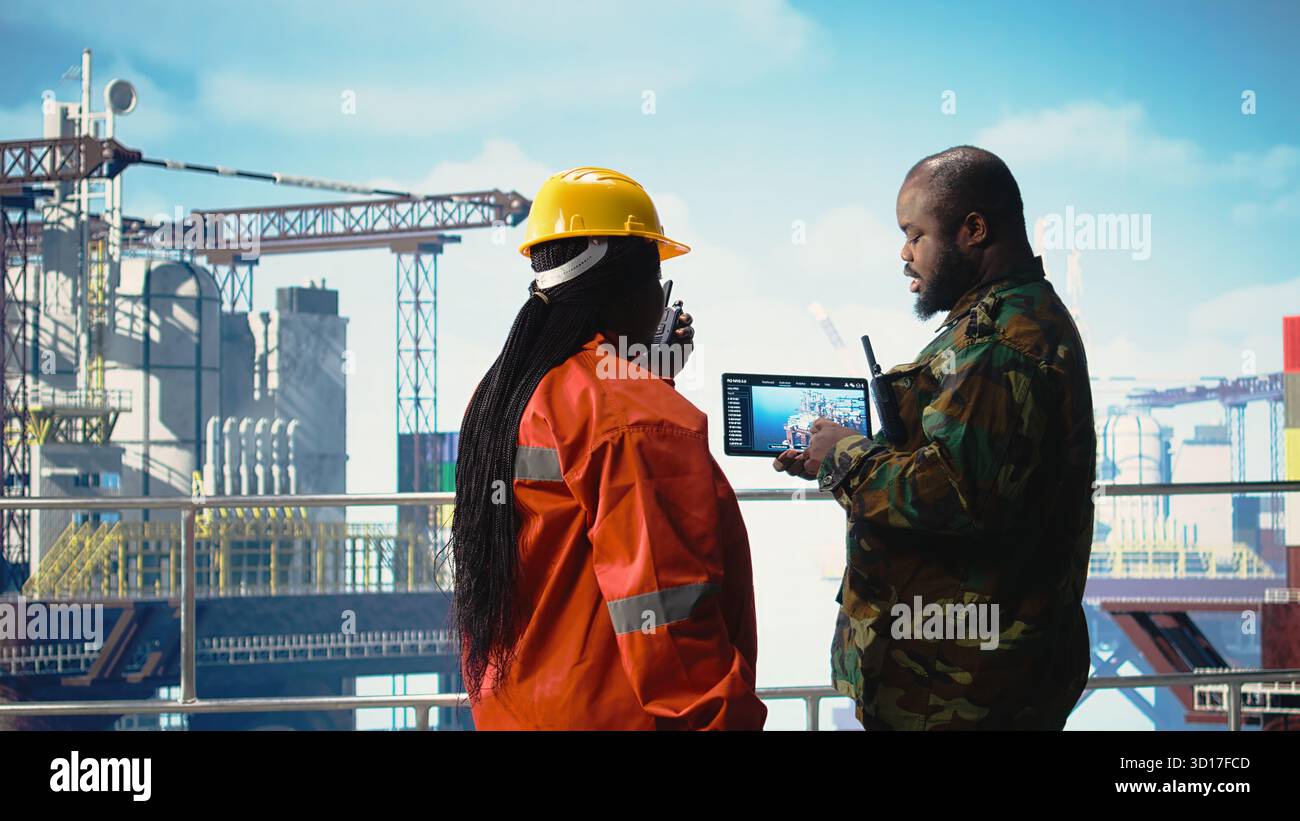 Guard Using Tablet Soldier on offshore platform deck talking with technician, using device ...