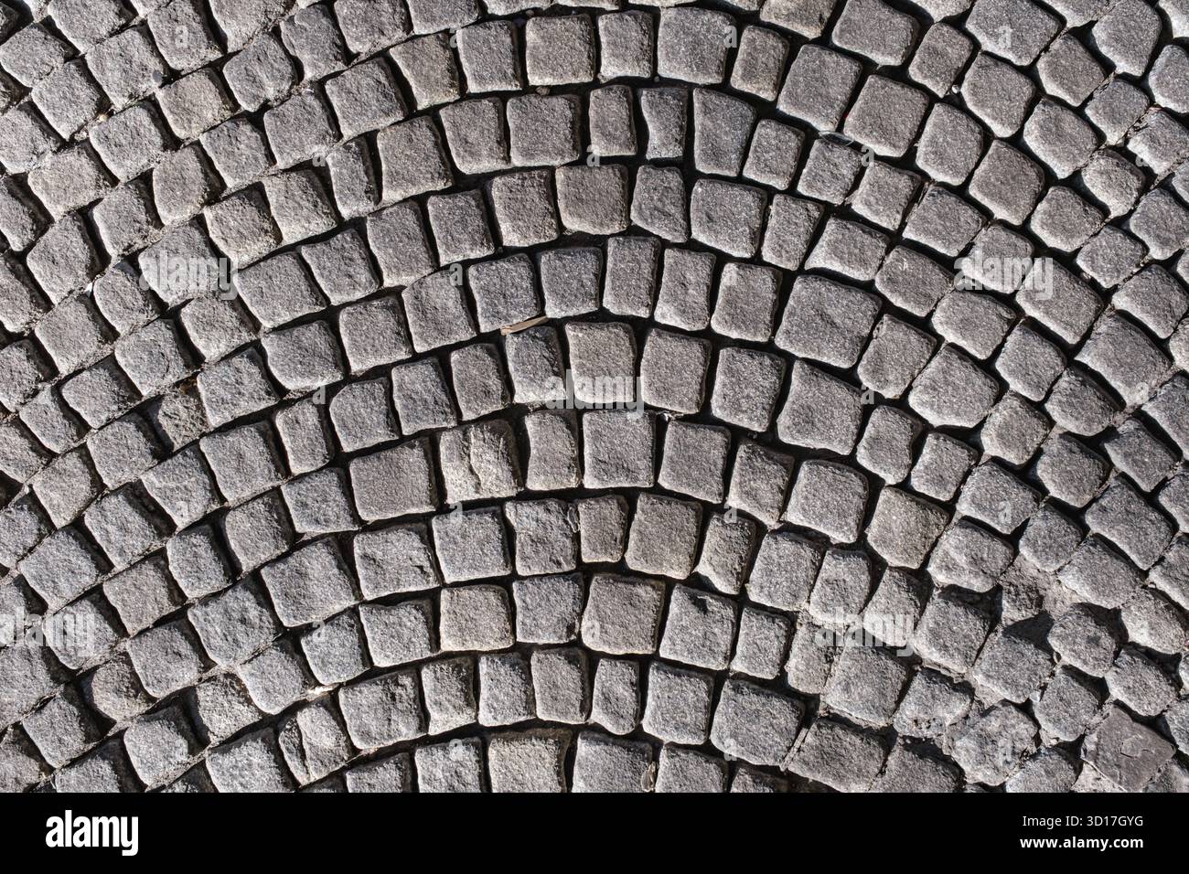 A textured cobblestone pavement arranged in a curved pattern Stock Photo