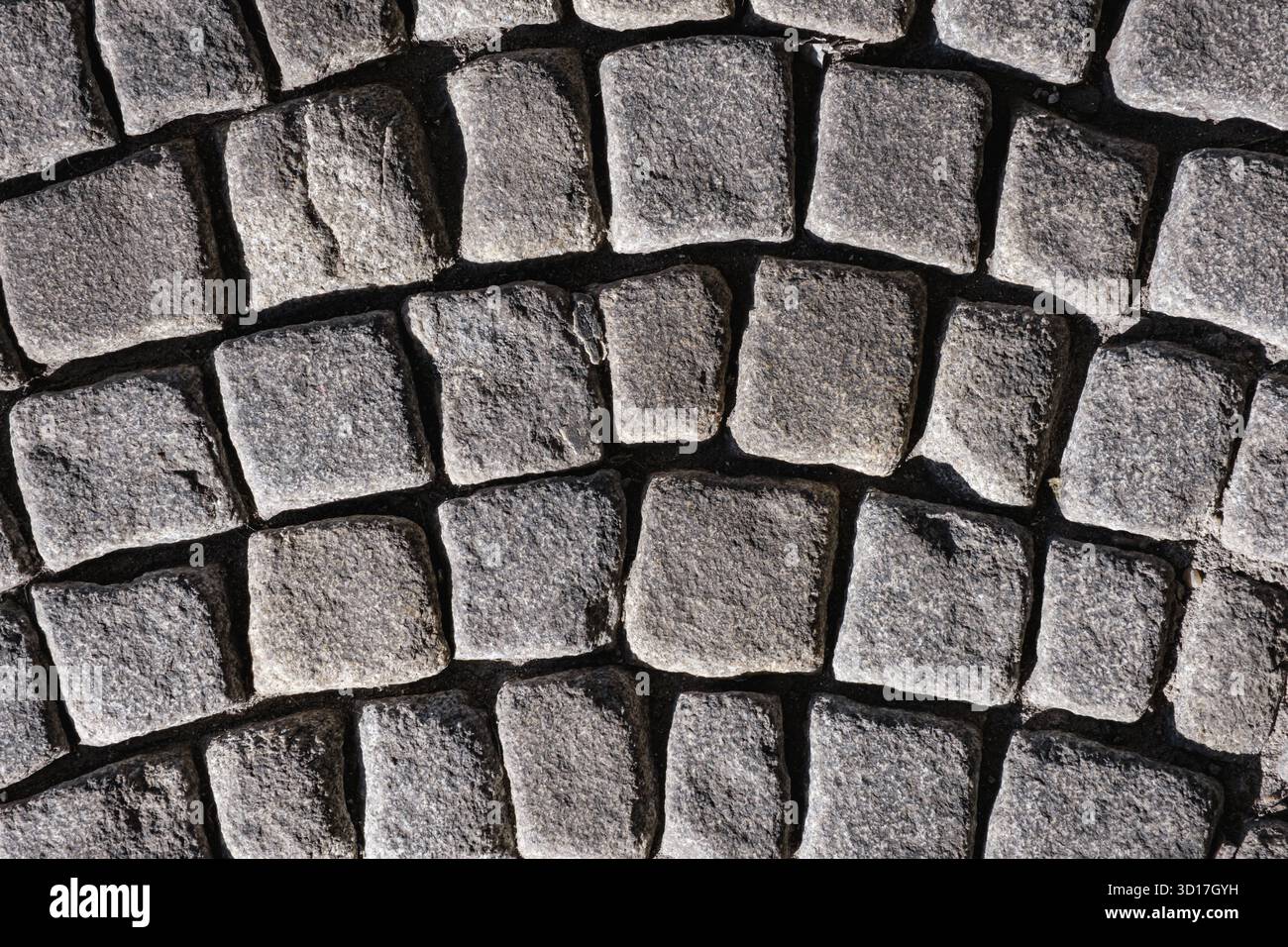 A textured cobblestone pavement arranged in a curved pattern Stock Photo