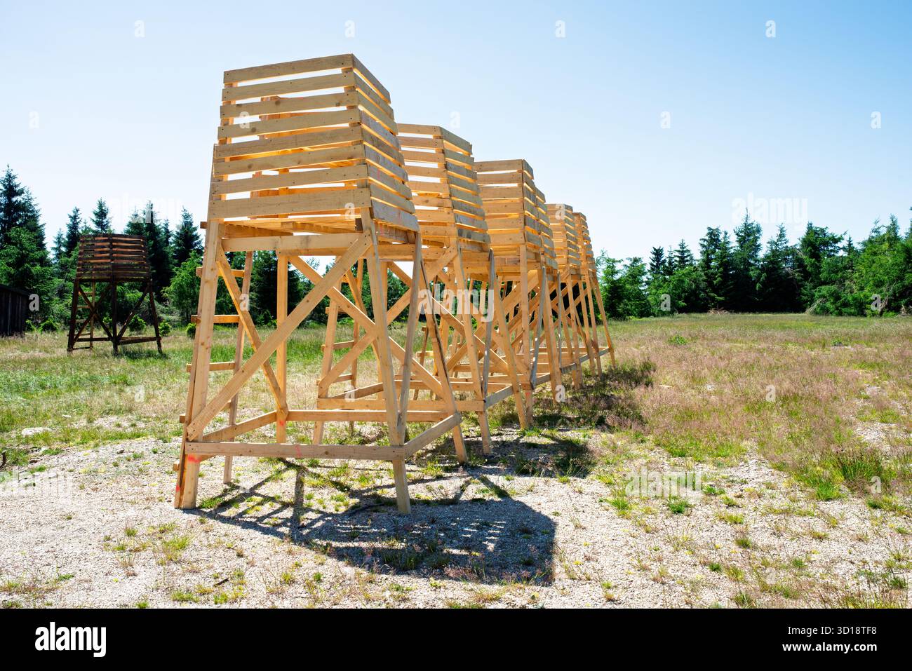 Row of elevated wooden observation platforms with ladders in open field ...