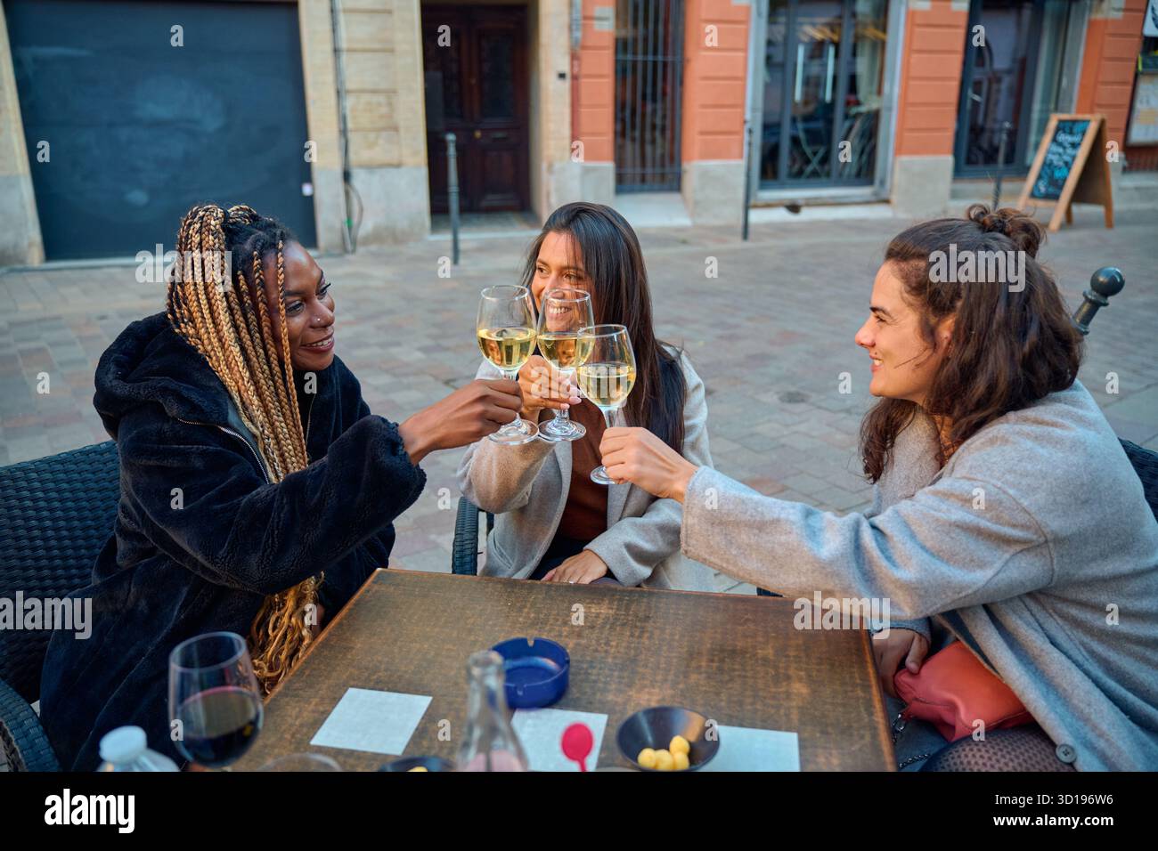 Diverse women friends toasting white wine in toulouse cafe Stock Photo