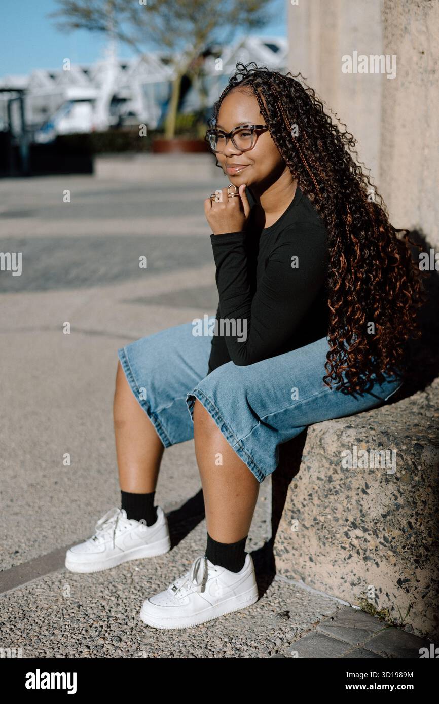 Young woman sitting outside in sunlight Stock Photo