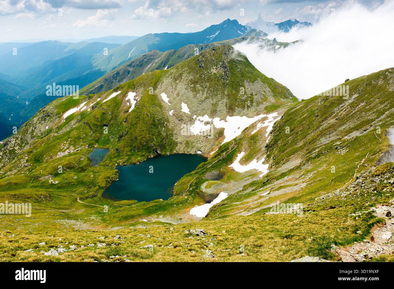 mountain landscape with alpine lake in summer. beautiful pond near popular hiking trail through transylvania alps of fagaras massif. postcard from rom Stock Photo