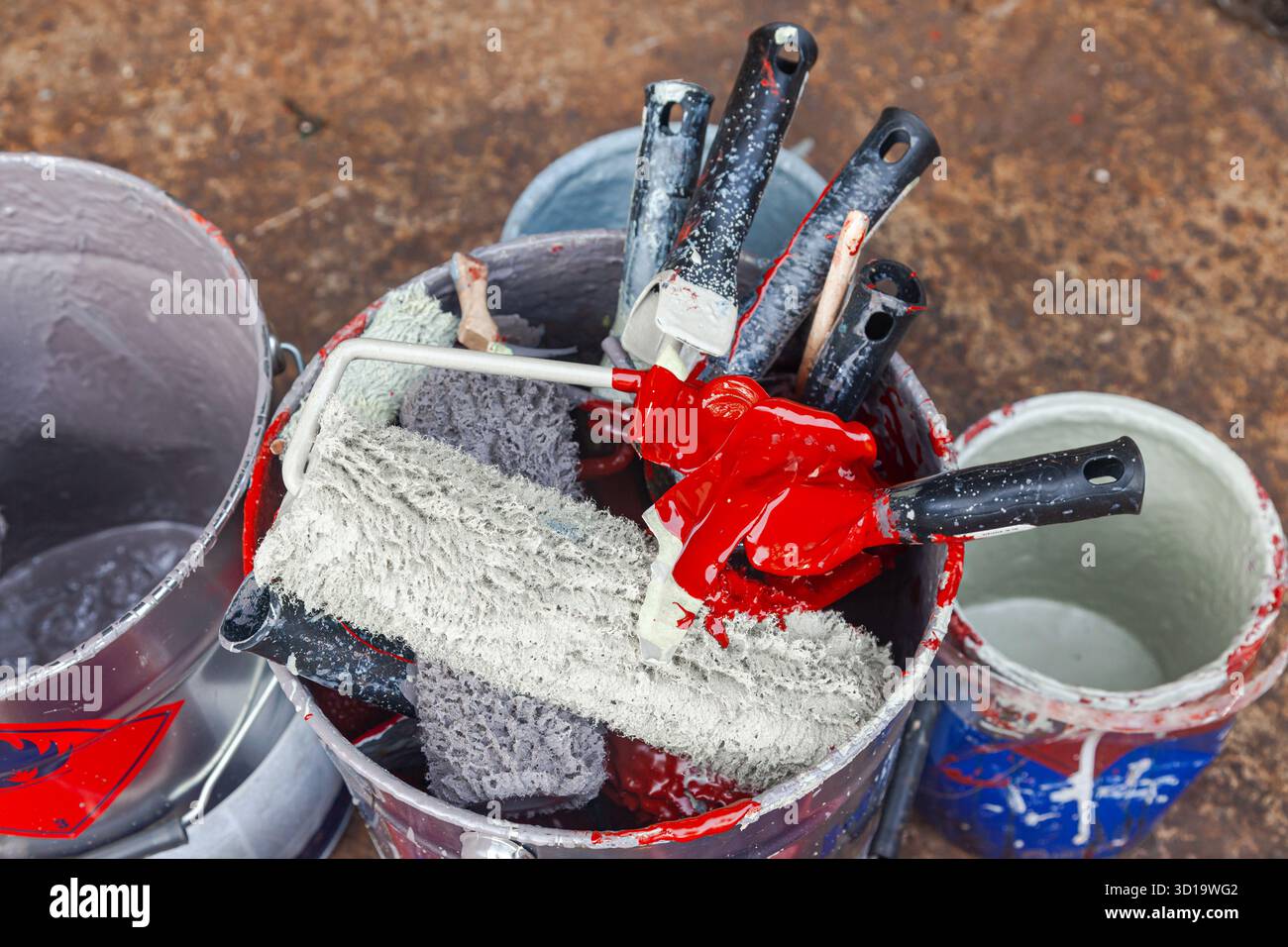 Empty paint buckets containing used rollers and brushes Stock Photo