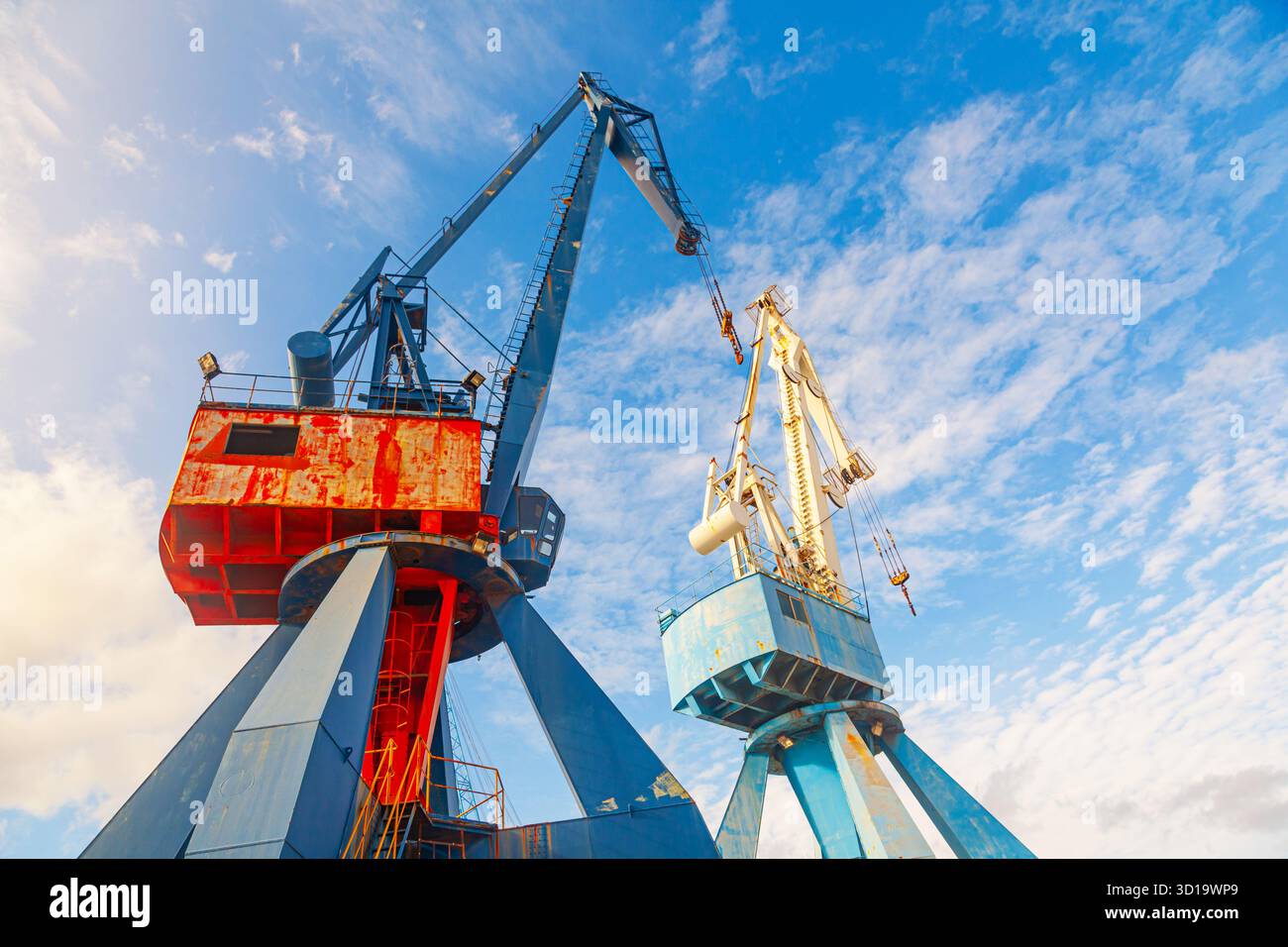 Two harbor cranes against a background of blue sky, bottom view Stock Photo