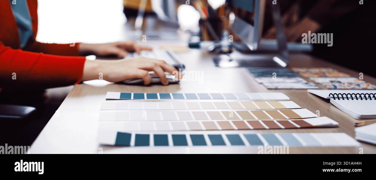 A vibrant creative workspace showcasing color palettes arranged neatly on a desk, featuring computer screens and design tools, ideal for artistic coll Stock Photo