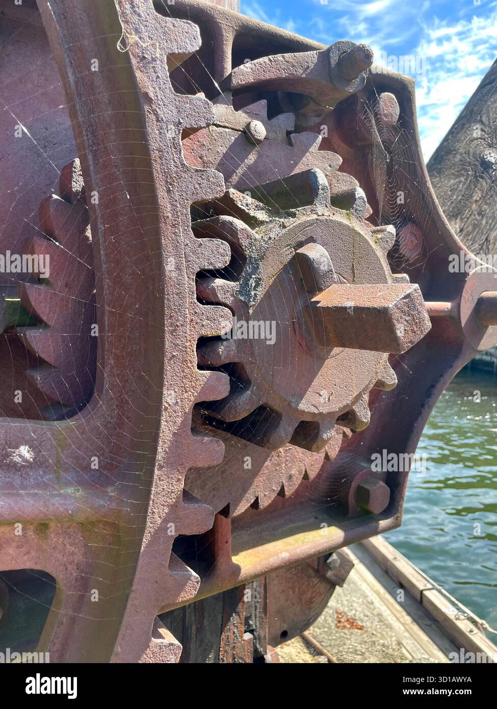 Close-up of rusty metal gear mechanism with a spider web, part of an old industrial machine, photographed in daytime. - Smartphone Captured Stock Image
