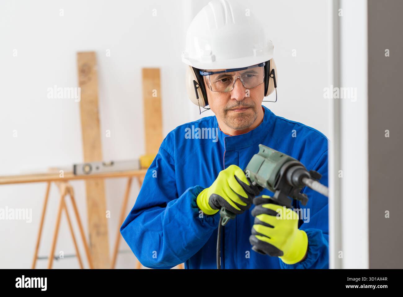 Construction worker working wrecking wall using rotary hammer in a building under renovation Stock Photo