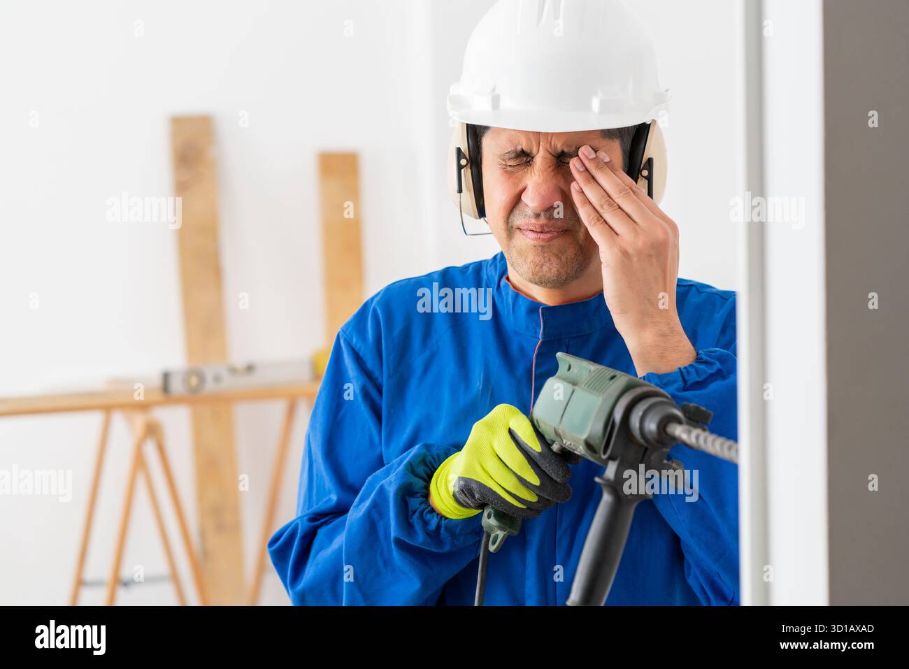 Construction worker suffering accident in an eye working with a electric drill without protection glasses at building Stock Photo