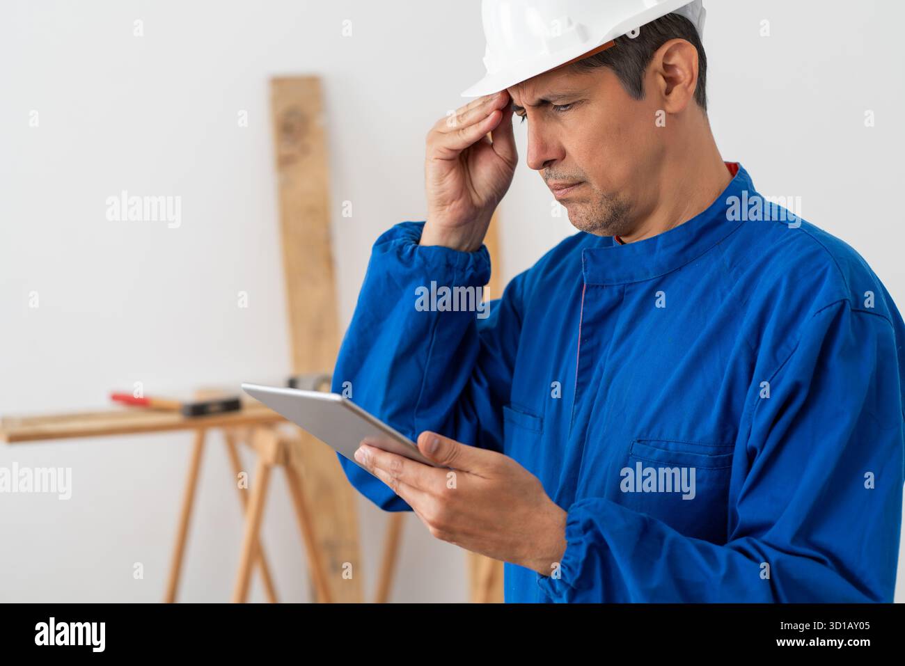 Worried construction worker checking tablet in a building Stock Photo