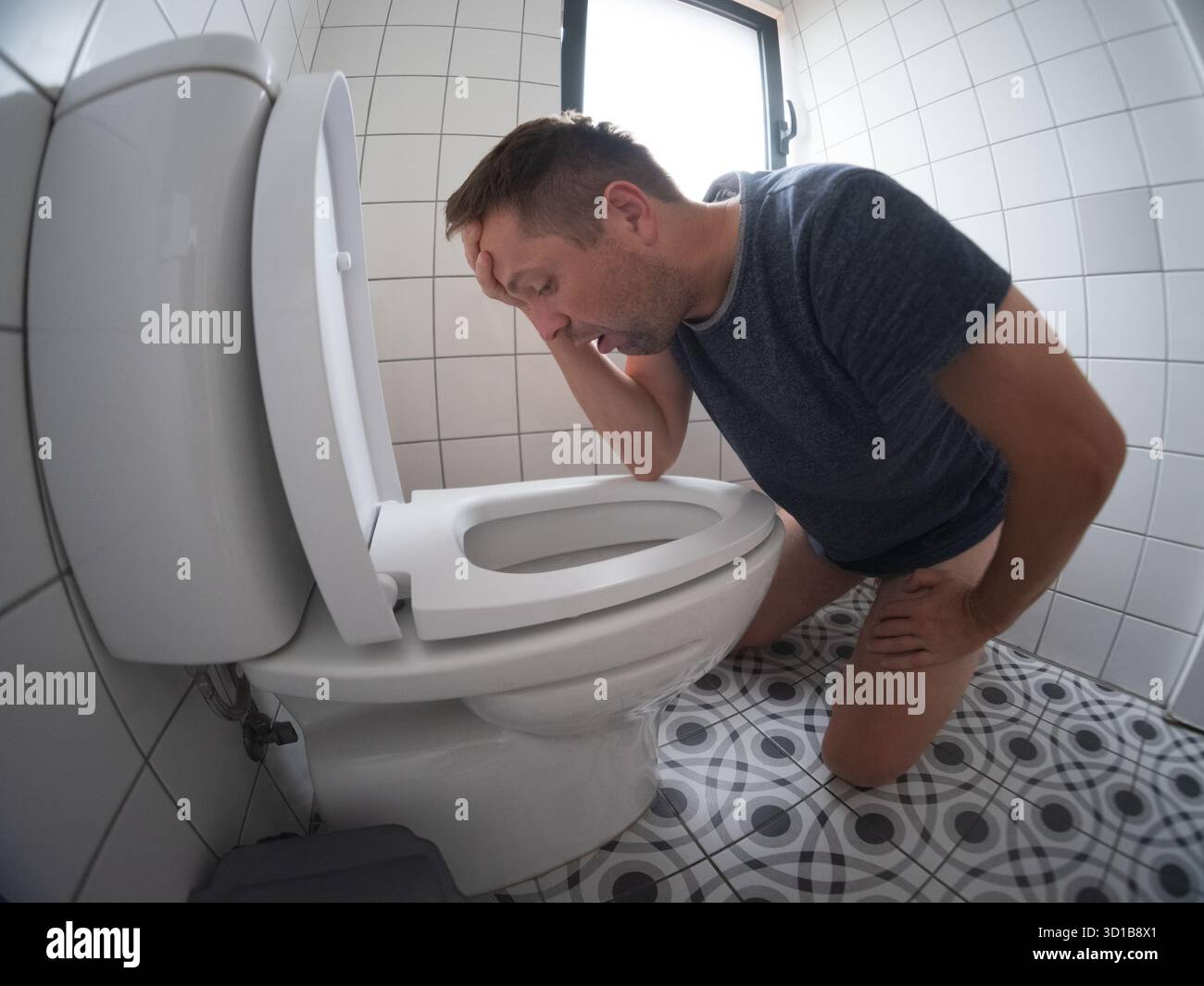 Man feeling sick by the white toilet after food poisoning Stock Photo