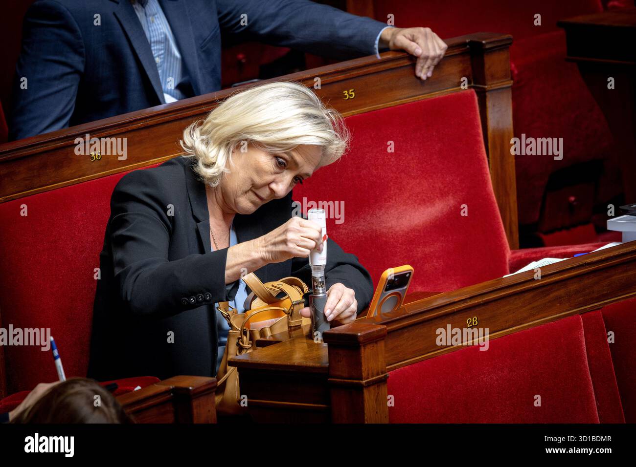 Paris, France. 27th Oct, 2025. President of Rassemblement National  parliamentary group Marine Le Pen fill her electronic cigarette (Cigarette  electronique CE) attends the examination a draft finance bill ( PLF/Projet  de loi