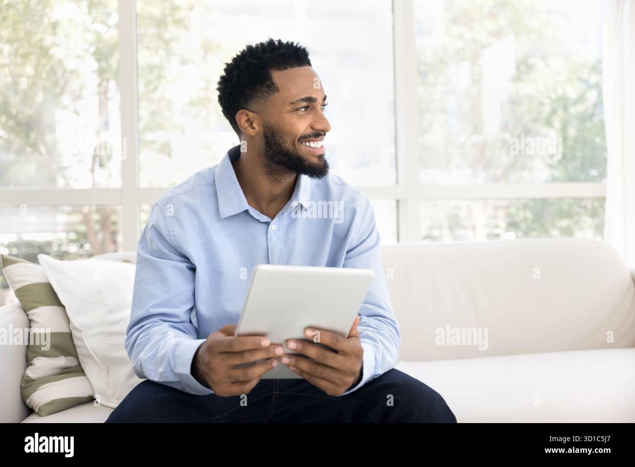 African man sit on sofa with digital tablet device Stock Photo