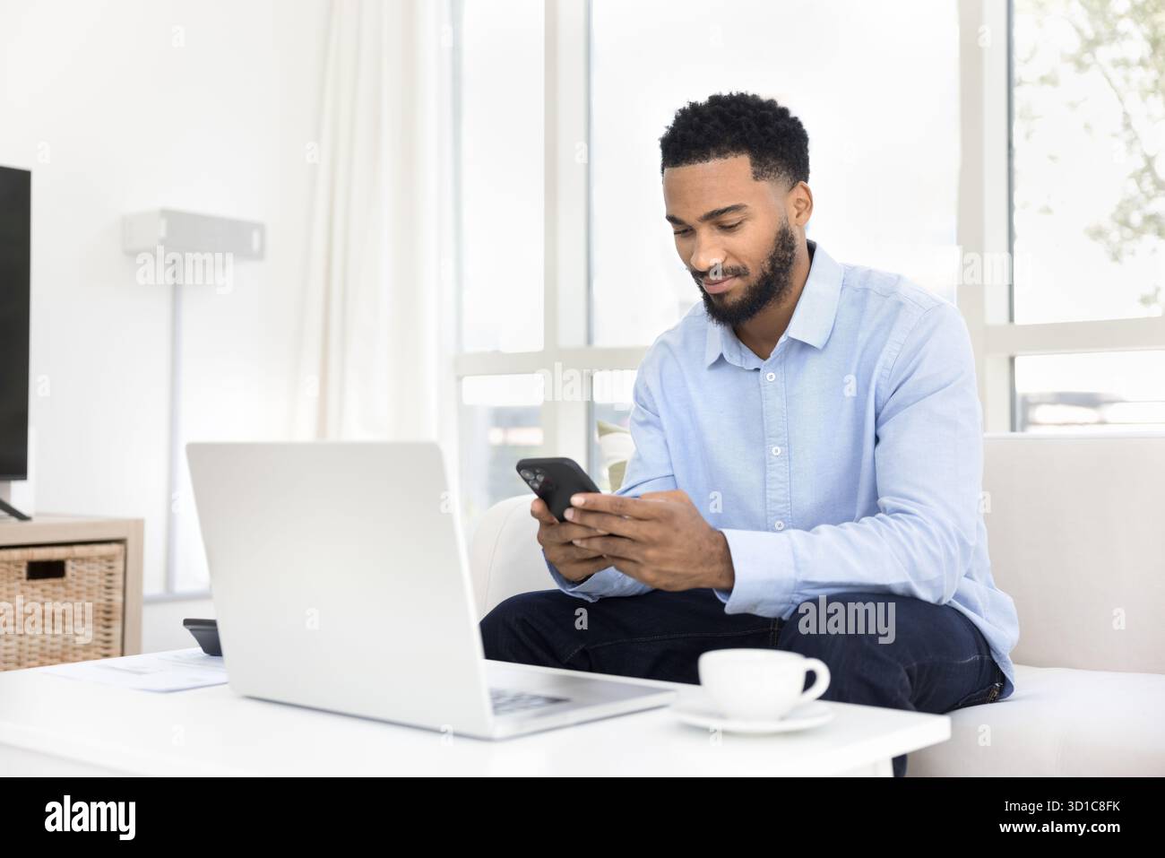 Focused man using smartphone seated on sofa Stock Photo