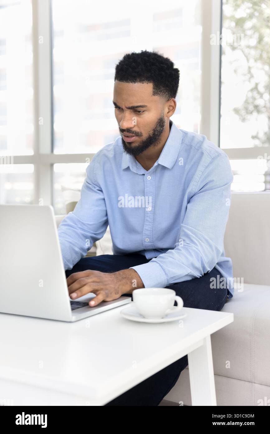Serious African man using laptop with serious and focused expression Stock Photo