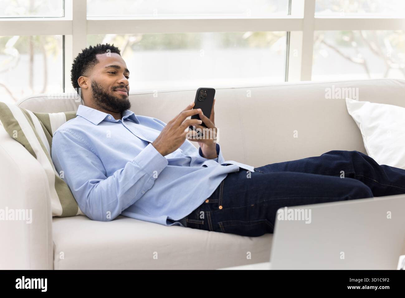 Relaxed African man spend free time on internet using smartphone Stock Photo
