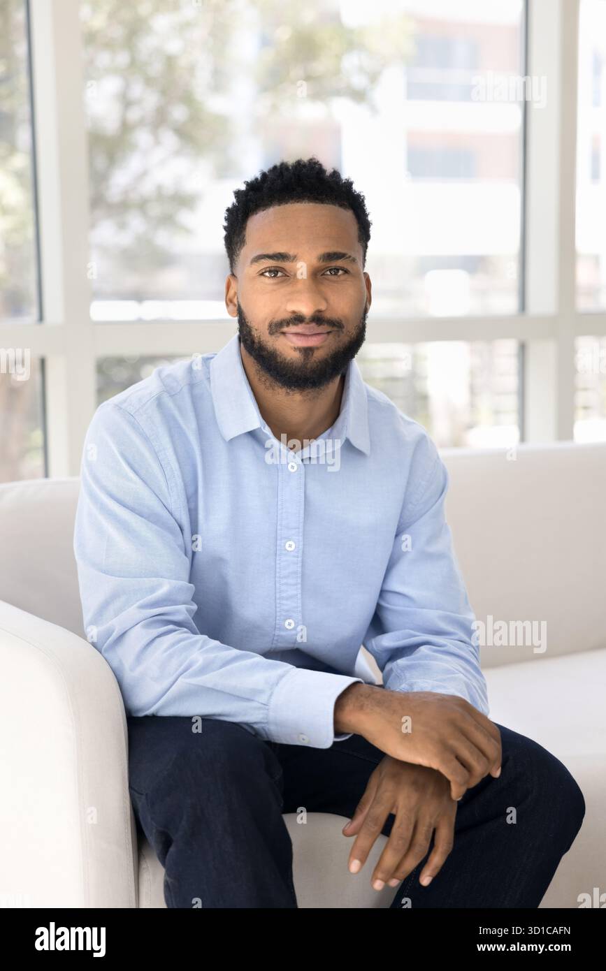 Handsome man sitting on couch looking at camera Stock Photo