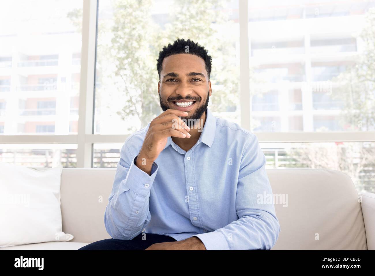 Man sitting on sofa gaze at camera with joyful expression Stock Photo