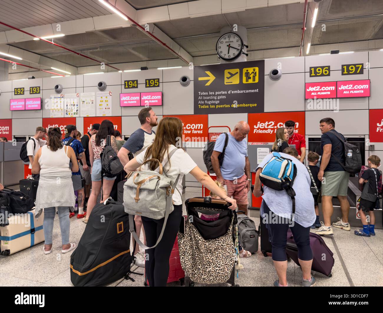 Travellers waiting in line with luggage at Jet2 check-in counters inside Palma Mallorca airport terminal with overhead signs and digital screens - Smartphone Captured Stock Image