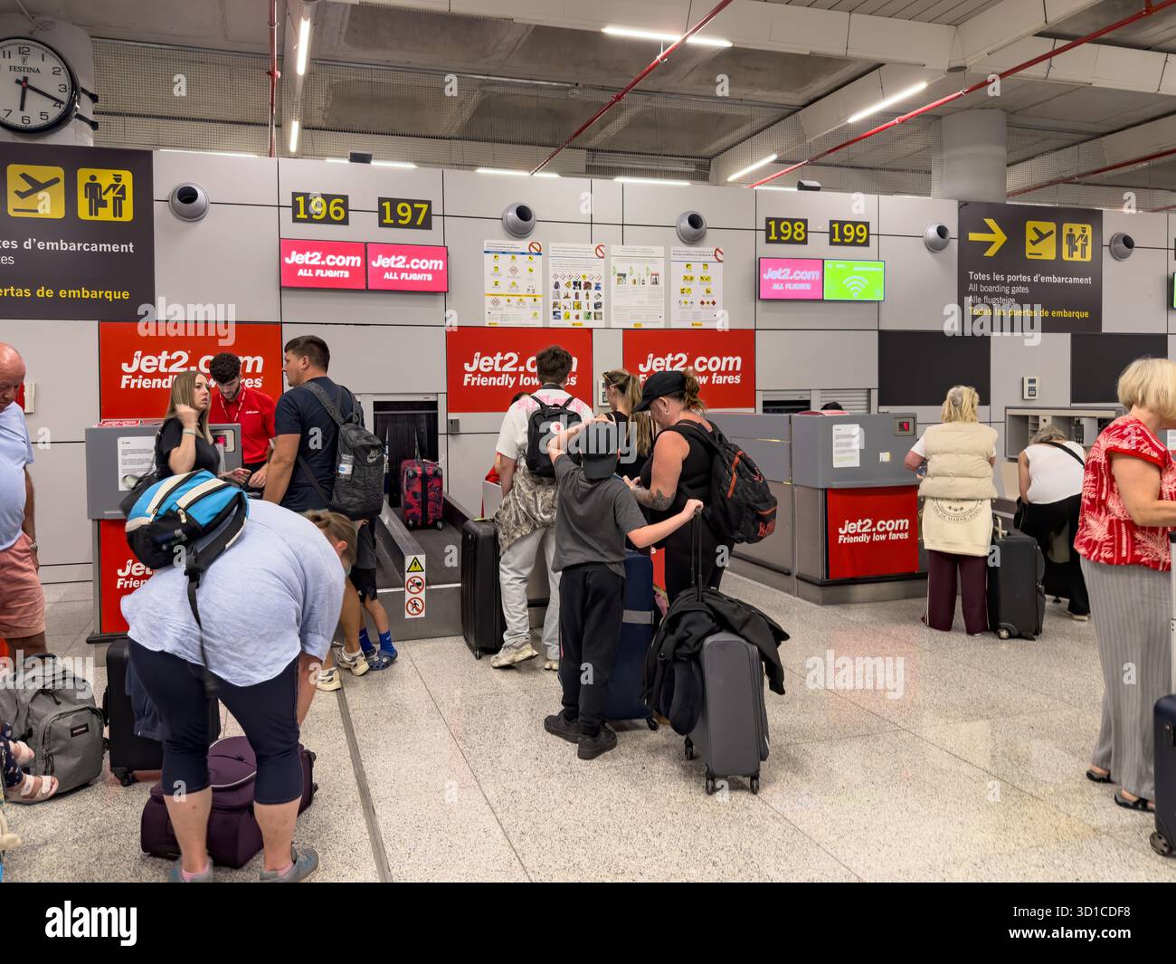 Travellers waiting in line with luggage at Jet2 check-in counters inside Palma Mallorca airport terminal with overhead signs and digital screens - Smartphone Captured Stock Image