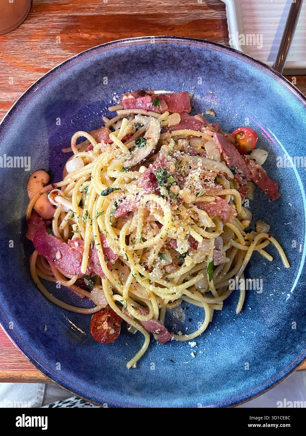 top view flat-lay, bowl of spaghetti carbonara with bacon cherry tomatoes herbs & grated cheese served in rustic ceramic dish on wooden table mallorca - Smartphone Captured Stock Image