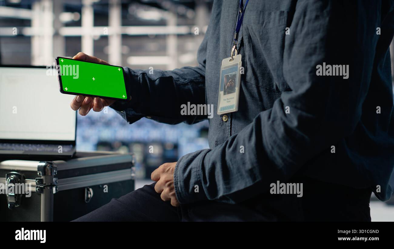 Data center worker uses isolated screen smartphone while deploying deep learning software. Server hub employee uses chroma key mobile phone while training AI systems with datasets, camera B Stock Photo