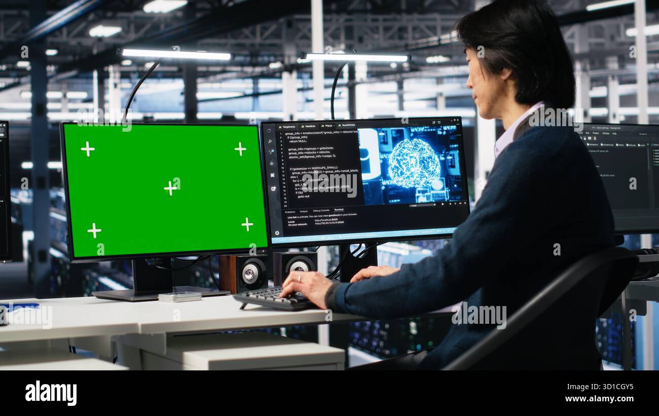 Data center admin typing on isolated screen PC keyboard, using AI. IT specialist at work using artificial intelligence on chroma key computer to oversee servers powering deep learning, camera A Stock Photo