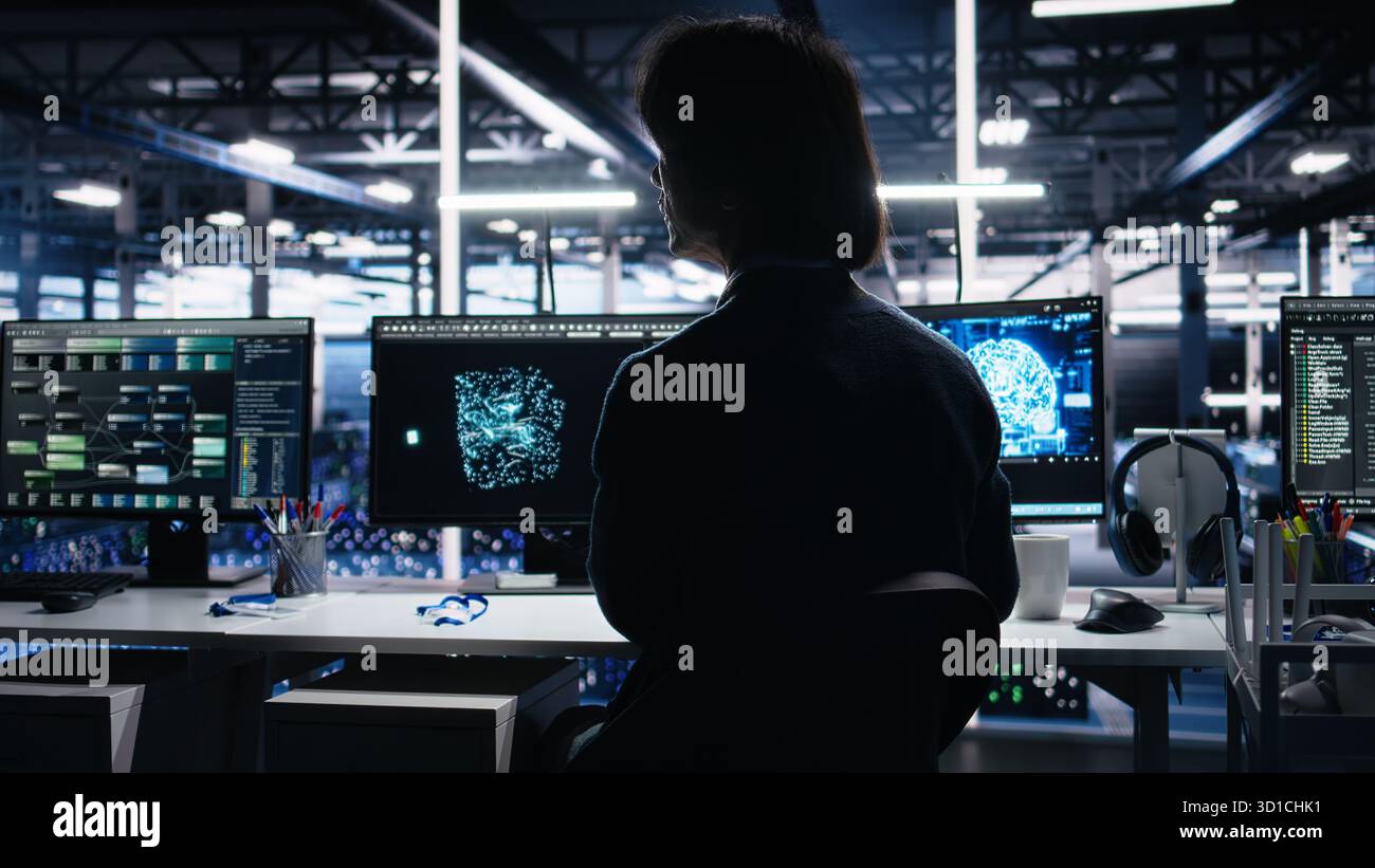Data center software developer using computer to monitor neural network AI LLM visualization. Worker in high tech facility using PC to oversee servers powering machine learning processes, camera A Stock Photo