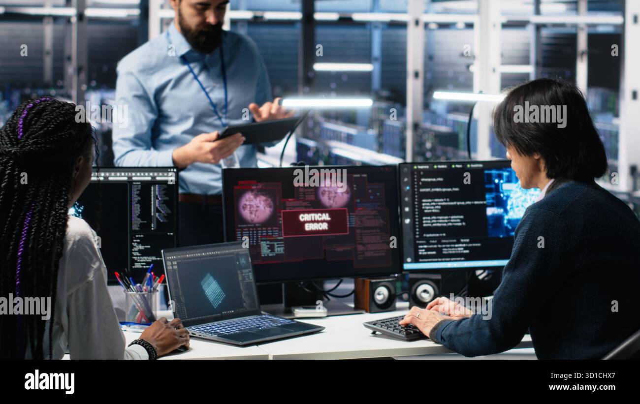 Data center manager coordinating programmers fixing critical error while using AI. Server room team leader overseeing workers repairing glitch popup while using artificial intelligence, camera A Stock Photo