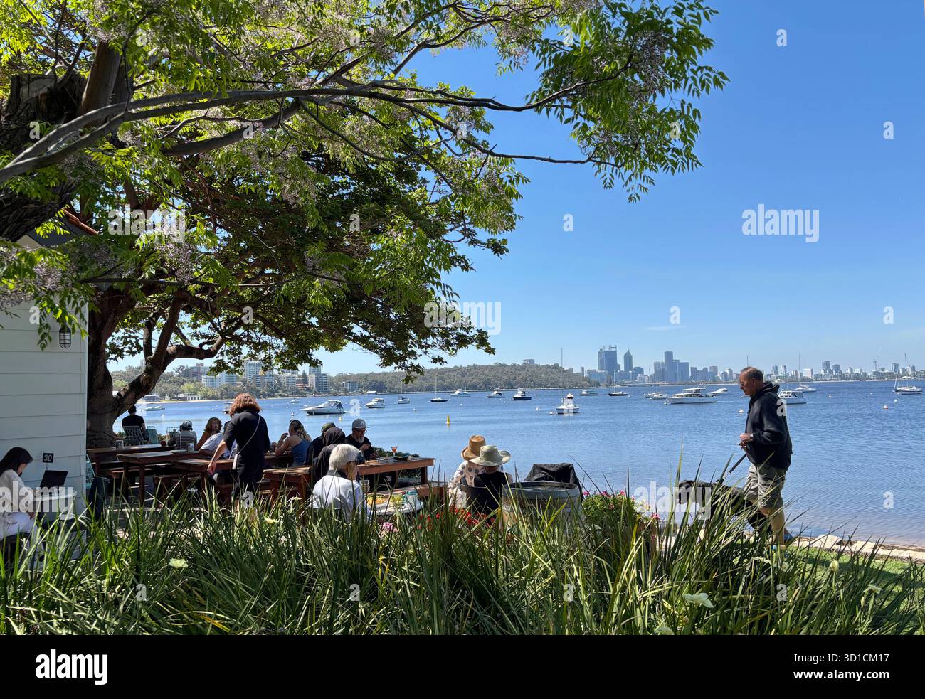 People eating and drinking on Swan River foreshore with Perth city skyline in the background, Bayside Kitchen, Crawley, Western Australia. No MR or PR - Smartphone Captured Stock Image