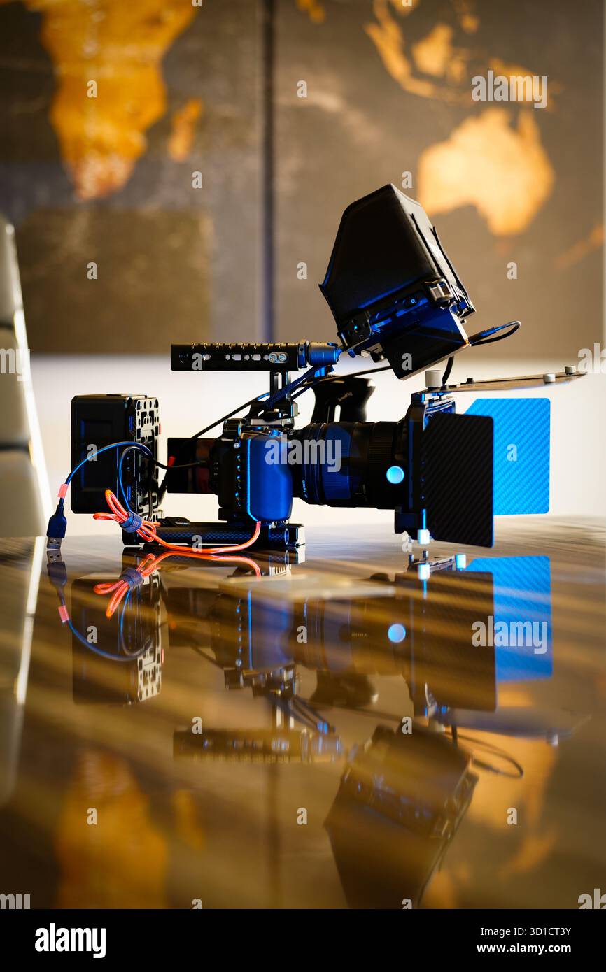 Professional video camera setup with full rig, external monitor, matte box, and cables on reflective surface concept of filmmaking, production, and cr Stock Photo