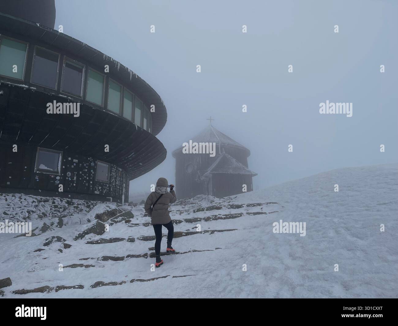 Polish Meteorological Observatory on Snezka (Śnieżka) Mountain Summit in Karkonosze, Poland, in foggy winter weather with a hiker.mountains - Smartphone Captured Stock Image