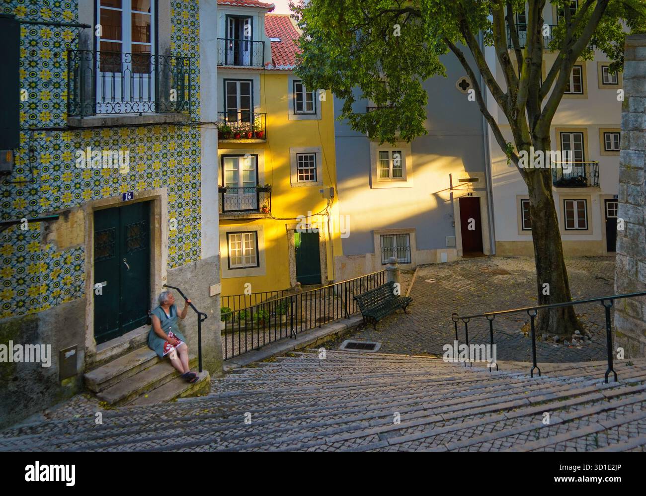 Eine Frau sitzt auf den Stufen vor ihrem Haus im ruhigen Alfama-Viertel in Lissabon, Portugal Stock Photo