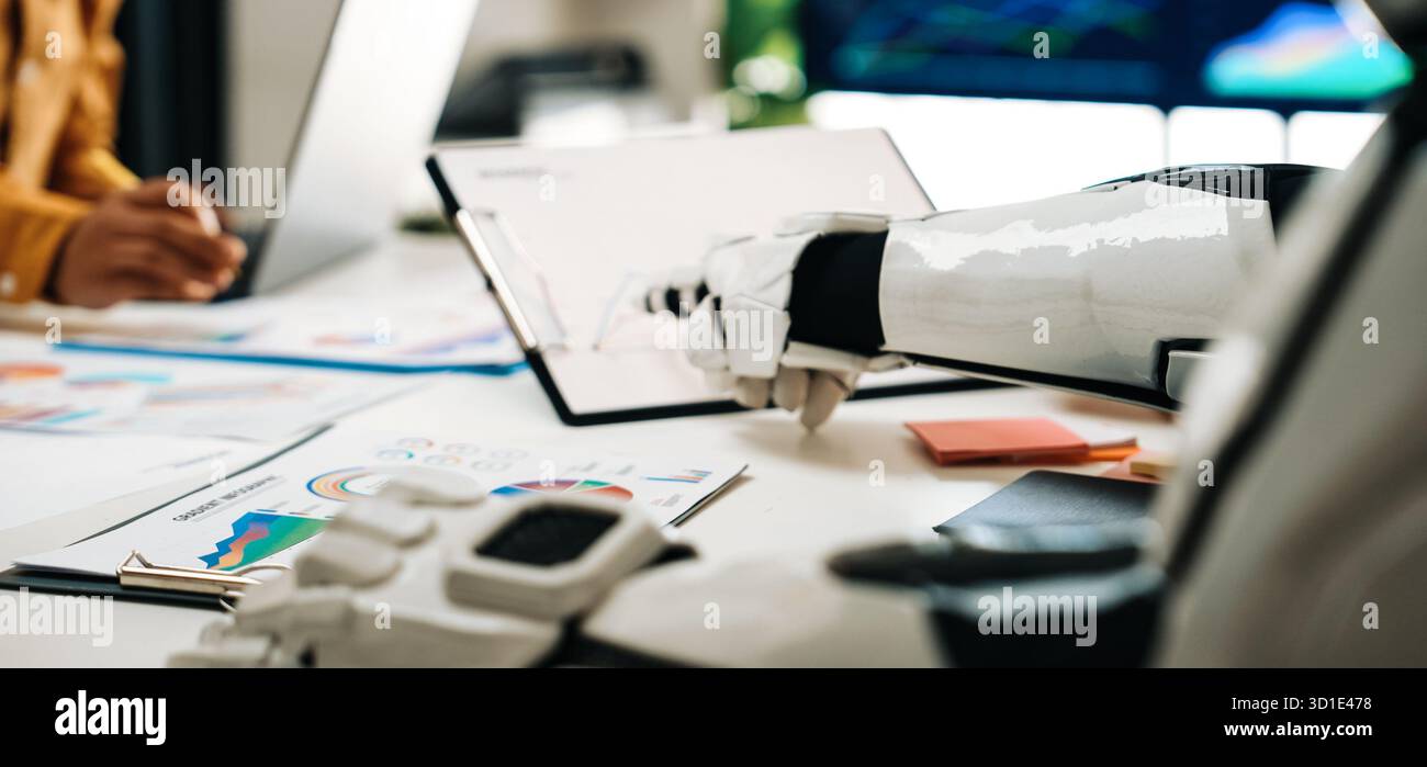 A modern workspace featuring a close-up of a robot hand collaborating with a human during a meeting, analyzing charts and graphs on the table that sym Stock Photo