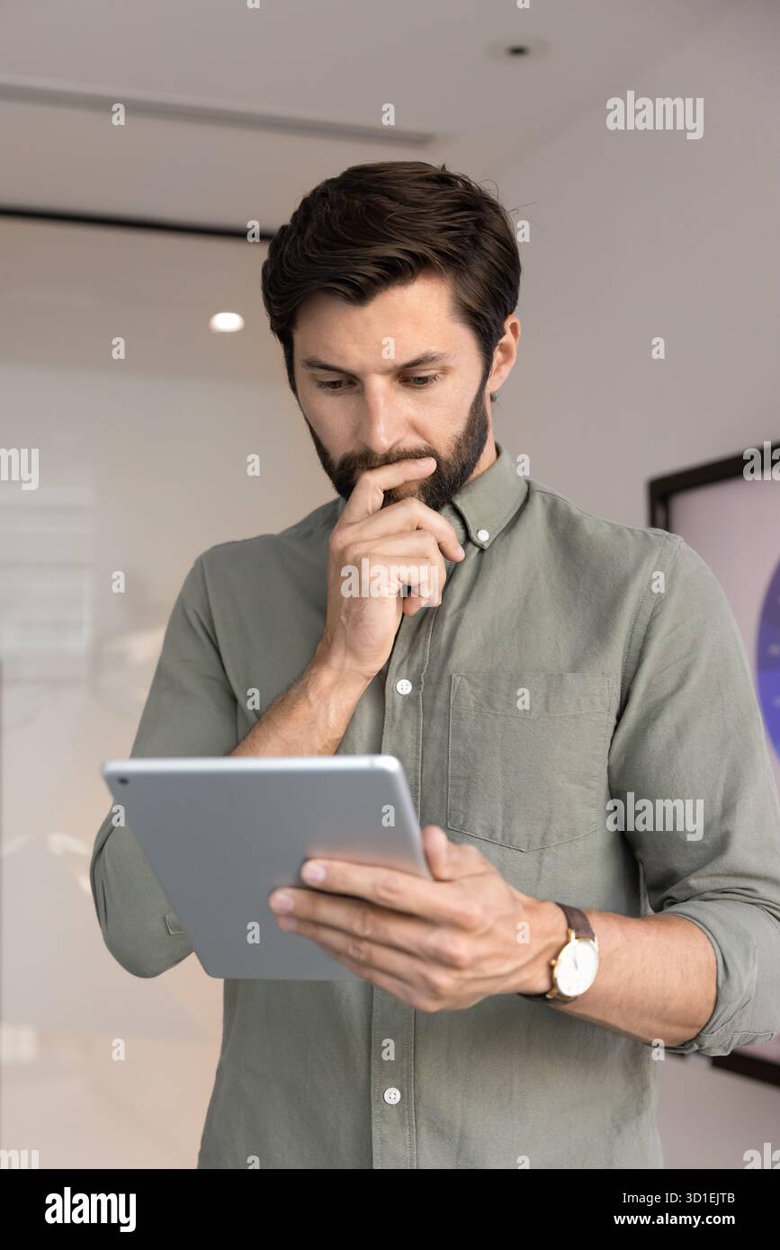 Thoughtful young 30s businessman using digital tablet Stock Photo