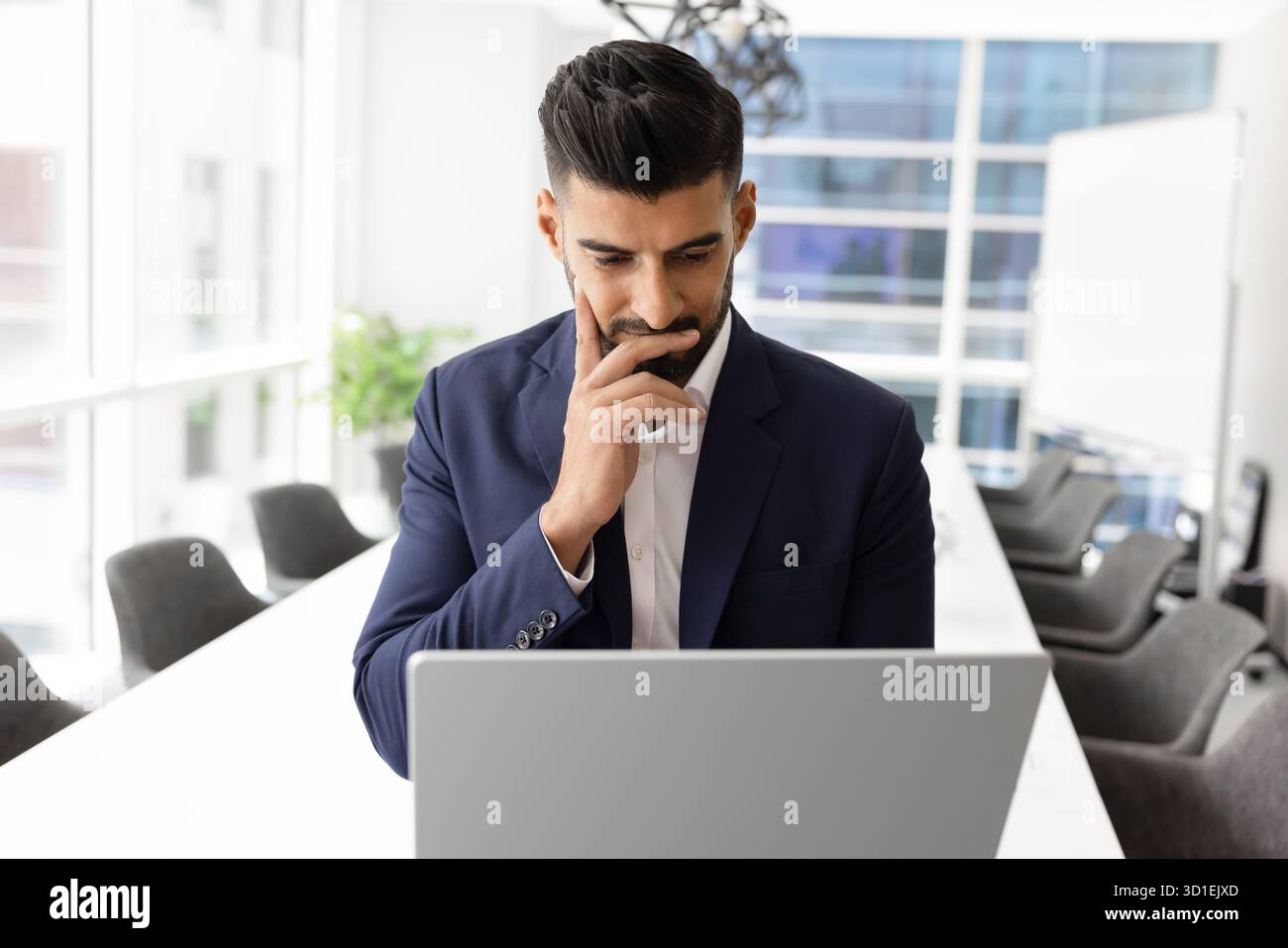 Pensive focused young Indian CEO man using laptop Stock Photo