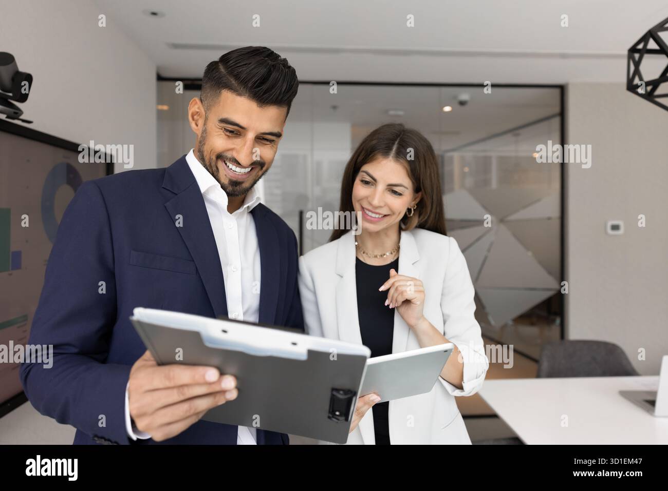 Diverse couple of positive office colleagues discussing documents on clipboard Stock Photo