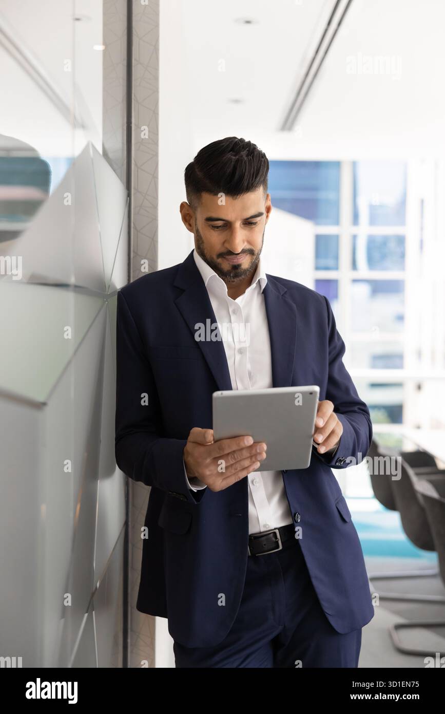 Serious young Indian CEO man typing on tablet Stock Photo