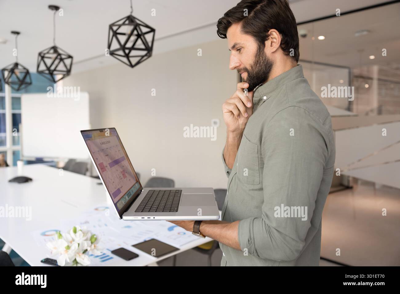 Positive thoughtful Caucasian project manager man using laptop Stock Photo