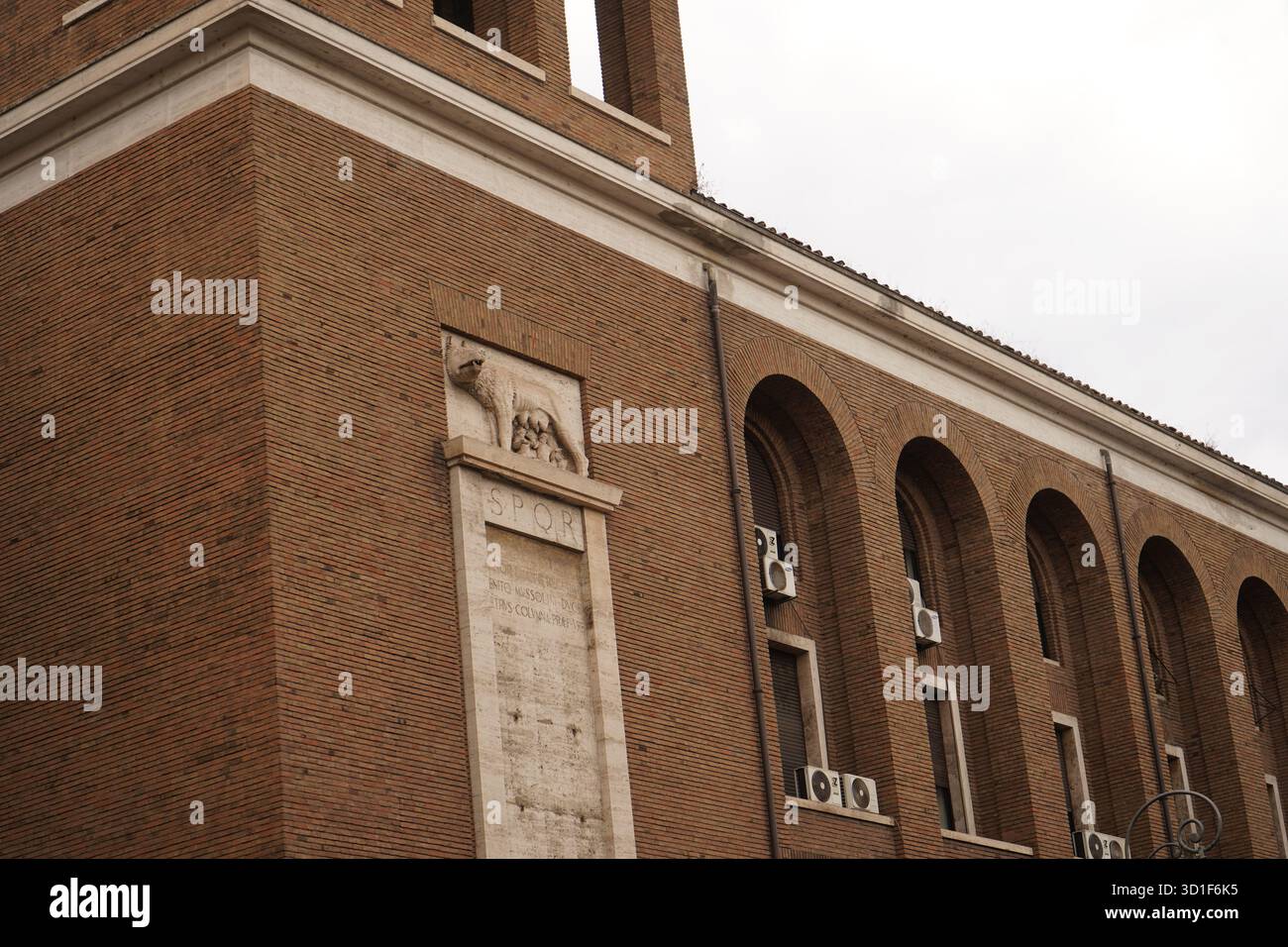 Detail of a brick building featuring the iconic Lupa Capitolina ...