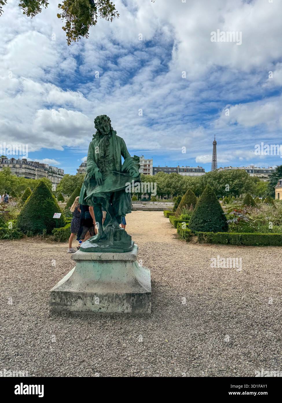 bronze statue in a formal french garden with trimmed hedges and gravel paths, on a bright day, with the eiffel tower is visible, - Smartphone Captured Stock Image