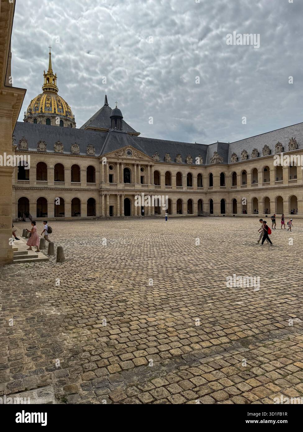 inner courtyard of les invalides in paris with symmetrical stone arcades, cobblestone ground and the golden dome visible under a cloudy sky, - Smartphone Captured Stock Image