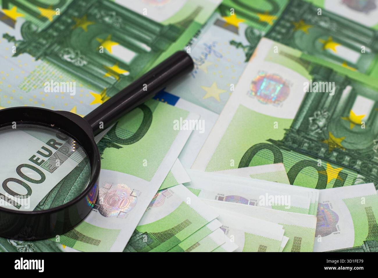 Magnifying glass examining one hundred euro banknotes close up Stock ...