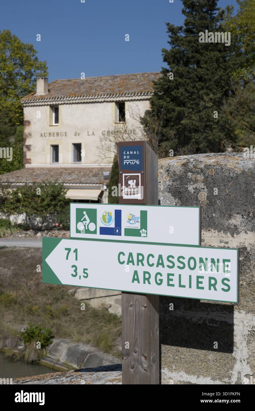 A signpost for cyclists along the Canal du Midi shows the distances to Carcassonne (71 km) and Argeliers (3.5 km) with green signs and logos. In the b Stock Photo